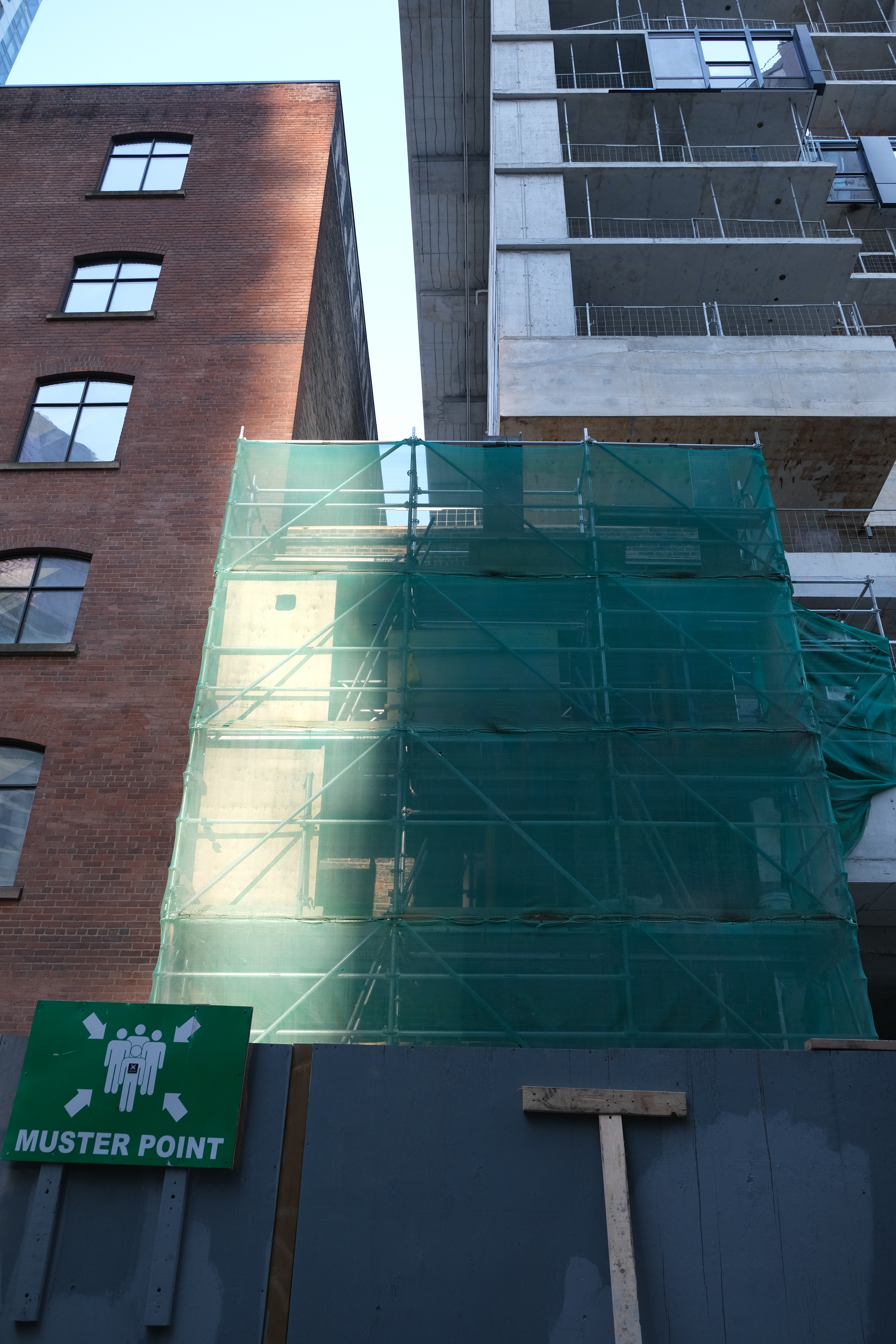 A colour image of a building seemingly under construction, covered in green netting.