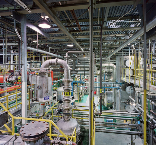 Busy image of many pipes, gears, and metal rods. The interior of the Sulfonation building, a Unilever plant.