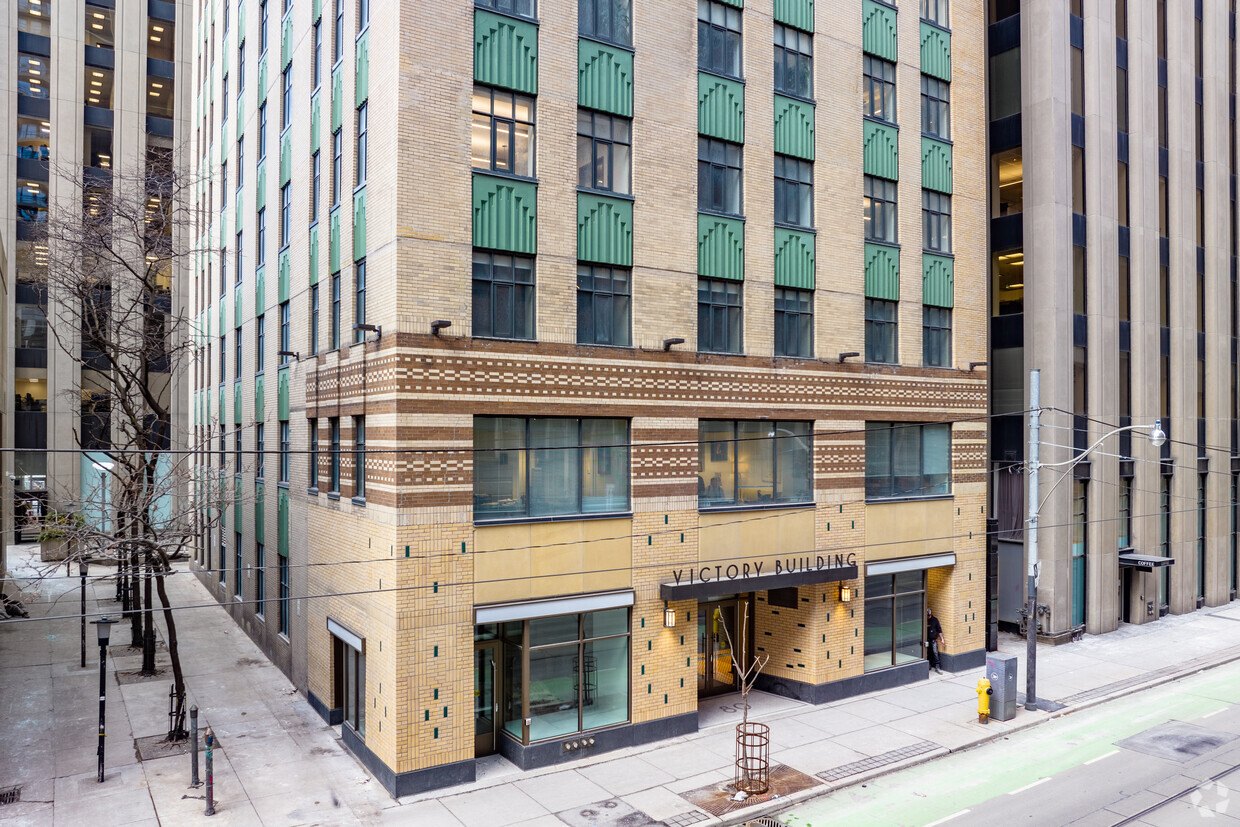 A large brown building with green details underneath the windows. The sign reads, "victory building."