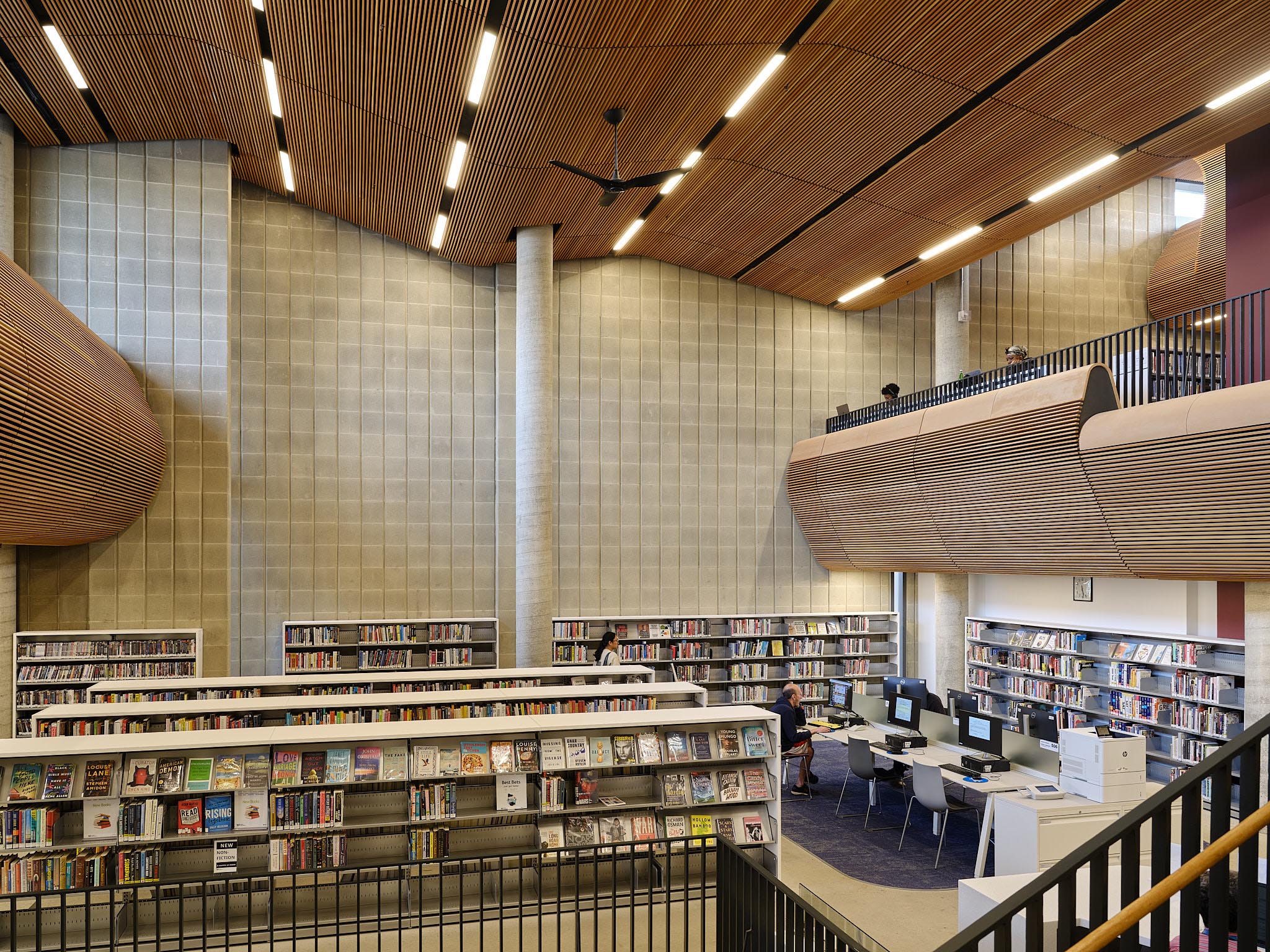 Interior image of a library with a curved roof and sides. Warm-wooden tones are present throughout.