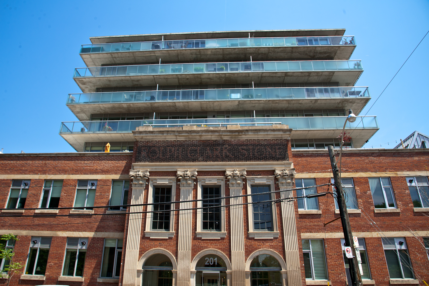 Old painted sign over the entrance to a three storey brick building with a modern condo building rising above and behind.