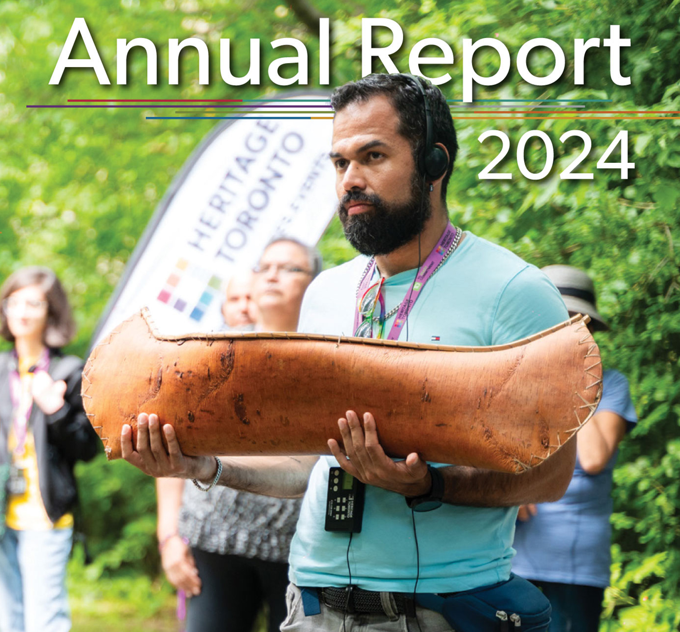 Detail of report cover with title Annual Report 2024 and showing people in a park with one person holding a model canoe.