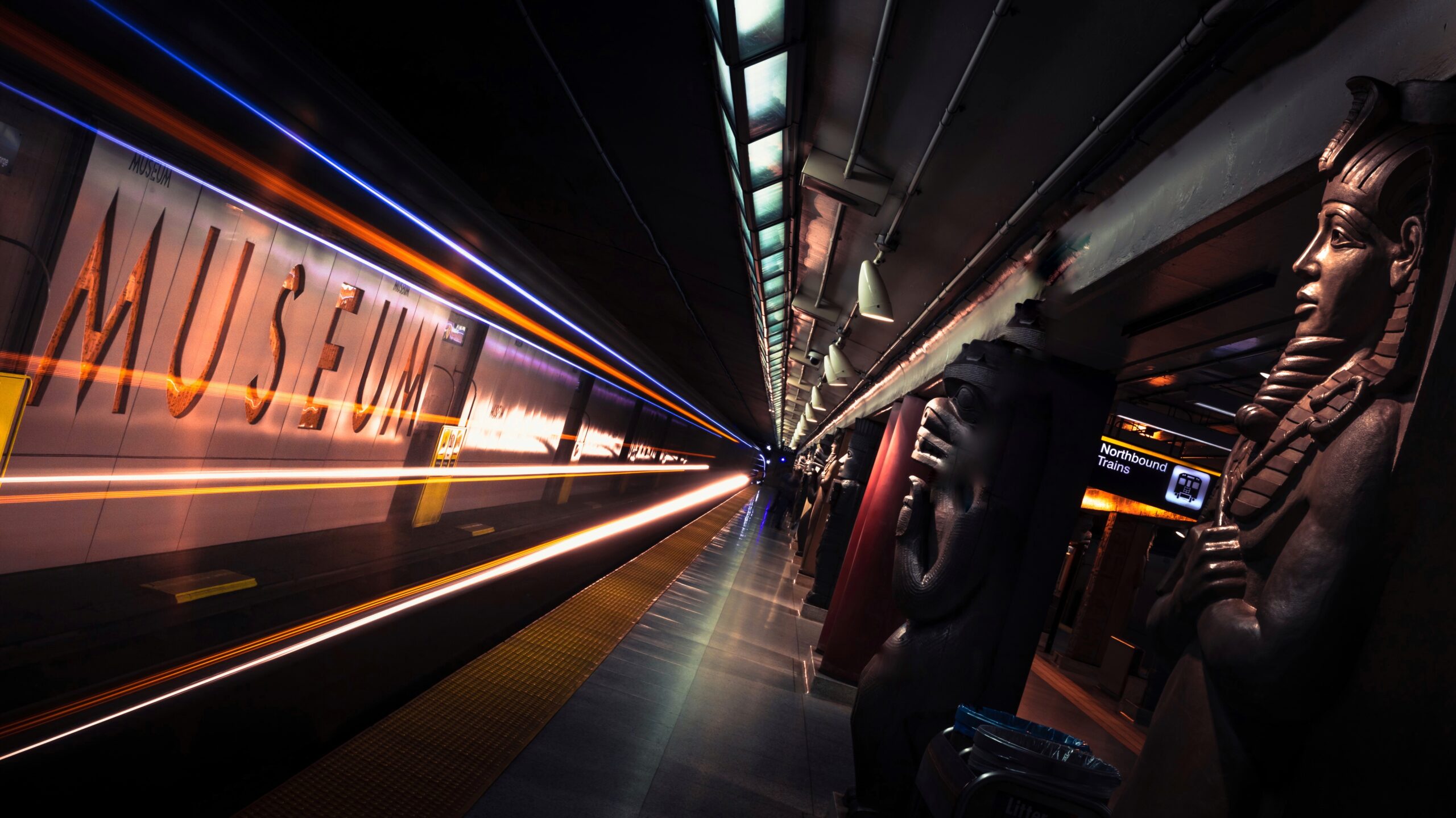 Long-exposure photograph of a subway station platform. Text on the wall reads "Museum".