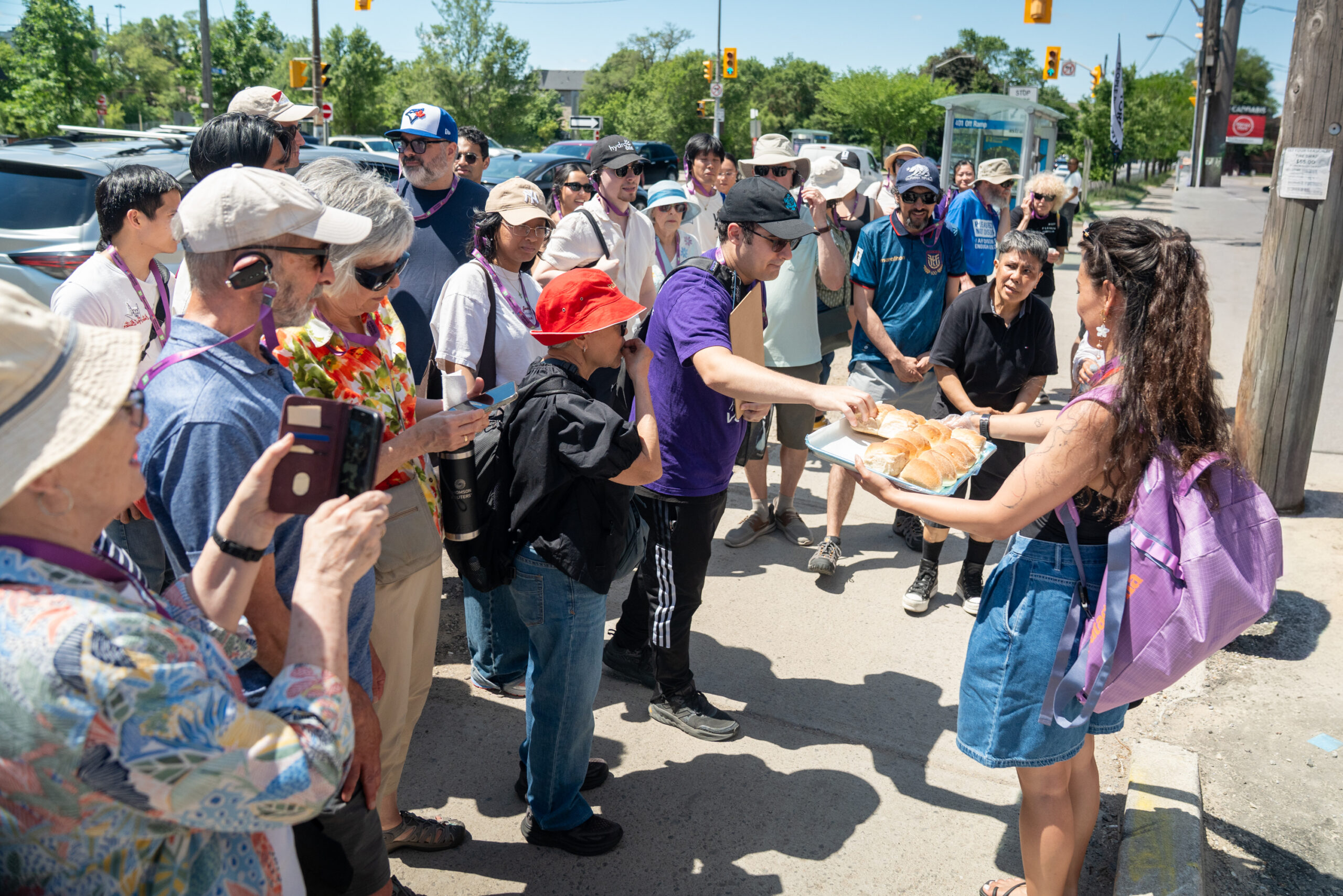 People stand around and take samples of bread-like loaves.