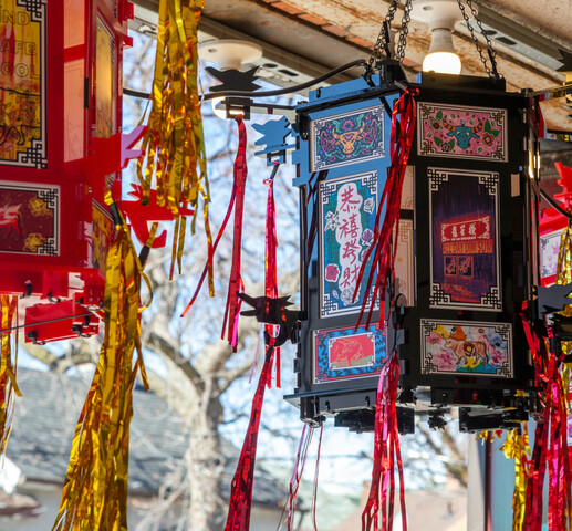 Image of Chinese lanterns. Middle lantern is black with red tassels hanging off. There are images of ox, flora, and Chinese writing. Lanterns to the left and right are red with gold tassels. They contain rectangular drawings with ox, koi fish, and writing that reads "BE KIND / BE SAFE / BE COOL / 2021".