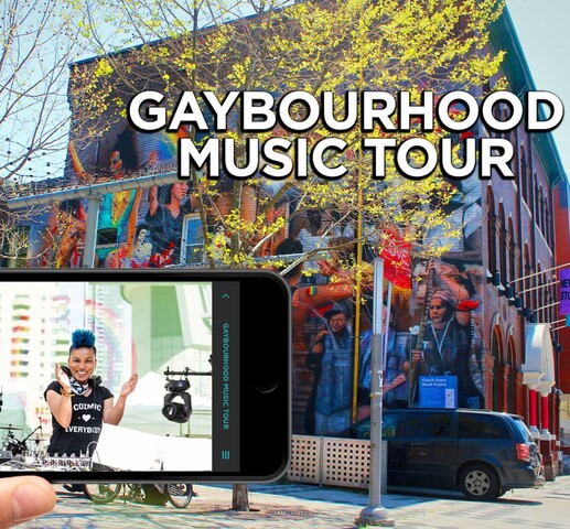 Poster image with a hand holding a smartphone horizontally. Smart phone displays a woman with blue hair wearing headphones with audio equipment on a table top. 'Gaybourhood Music Tour" is written in bold, uppercase letters in the top right corner of the image. There is a large building with mural art in the background.