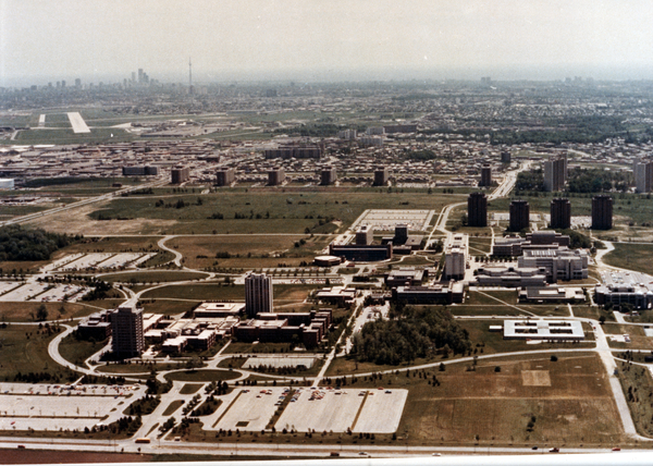 Aerial view of a complex with multiple buildings and connecting roads visible. A more intensely developed area appears in the background.