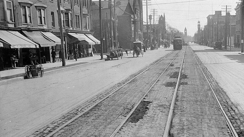 Streetcar tracks along a road with brick buildings on both sides.