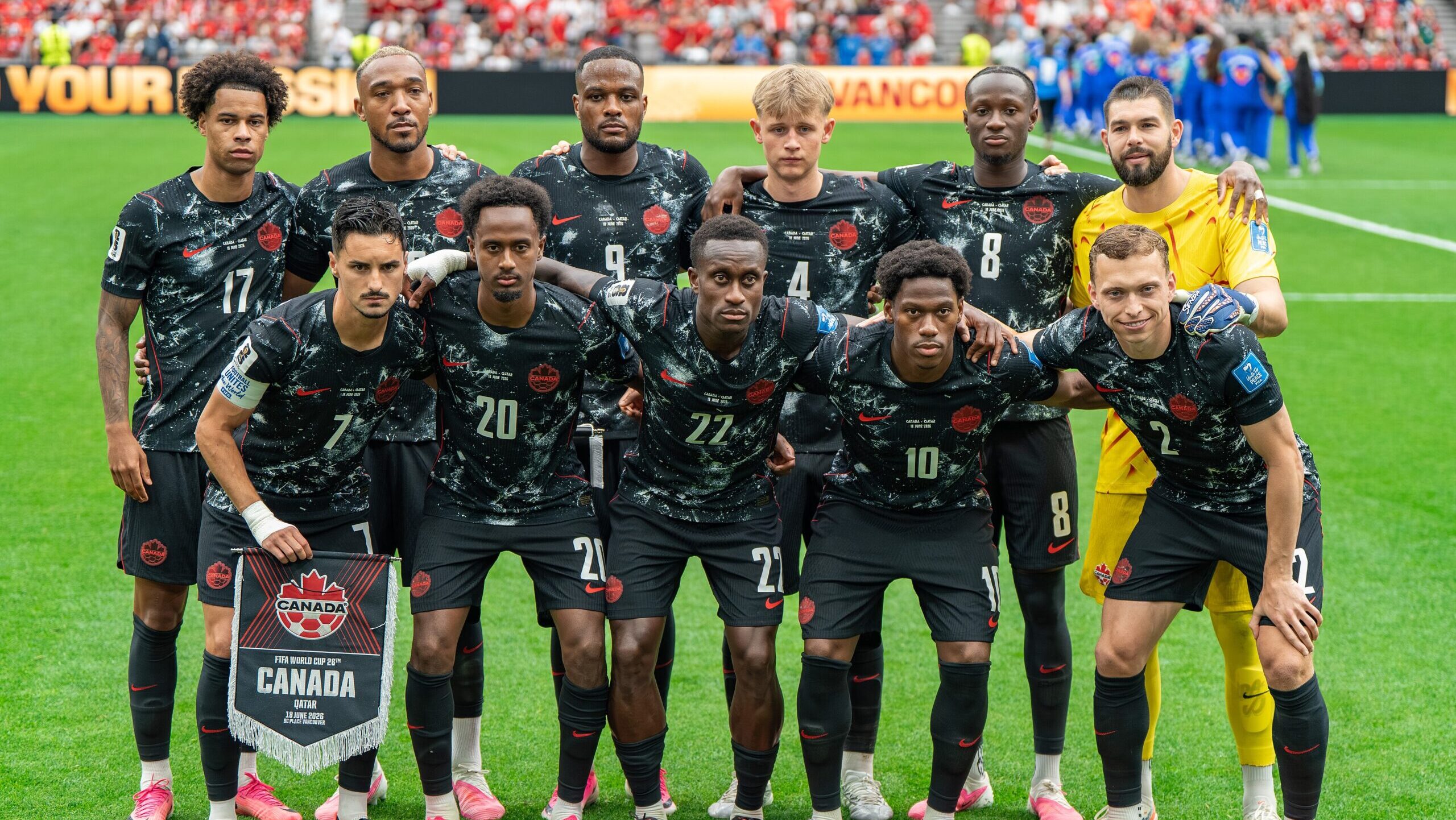 11 people wearing soccer jerseys posing for a picture in two rows.