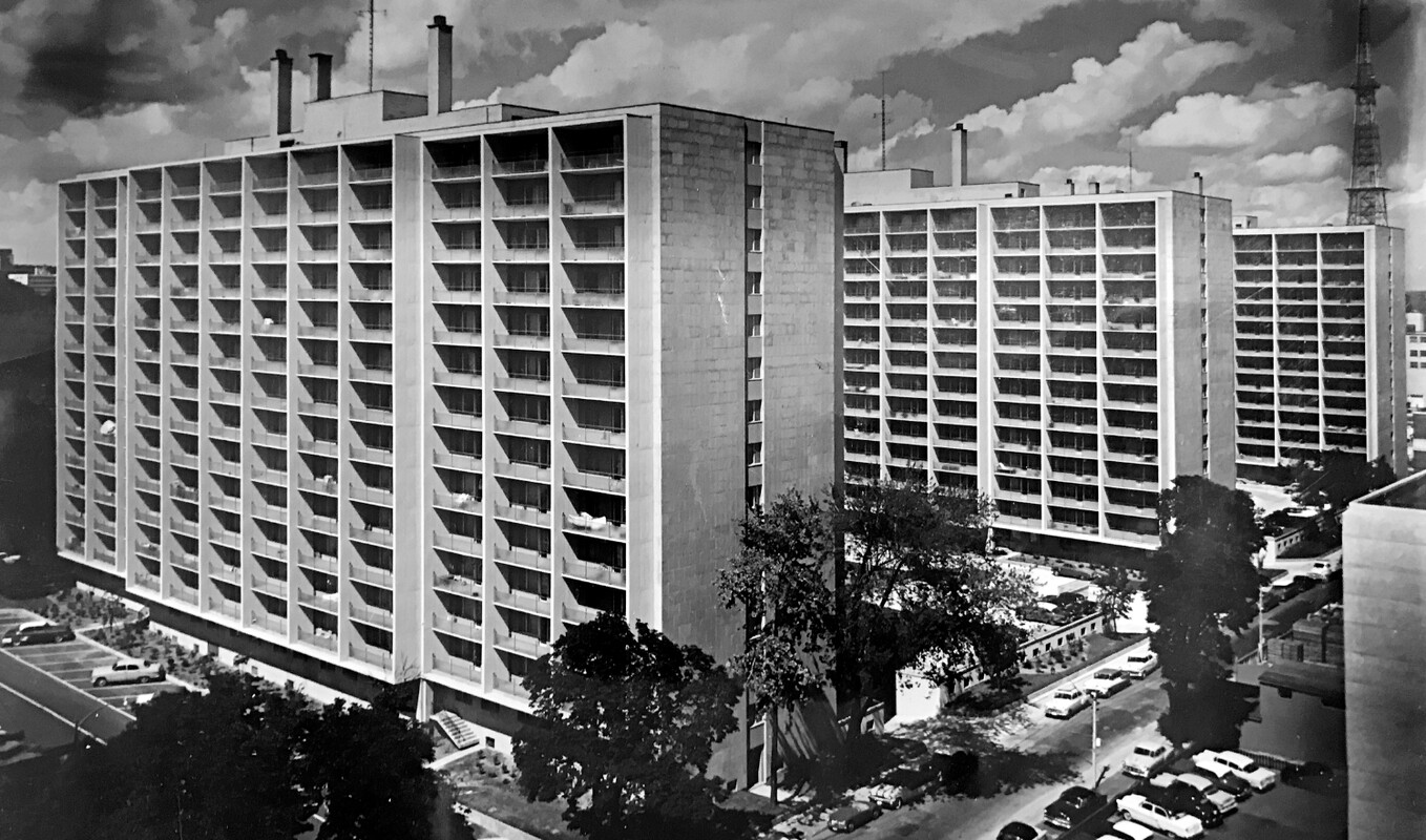 Slight aerial photo of three identical apartment buildings in a modern, post-war architectural style arranged in a row.