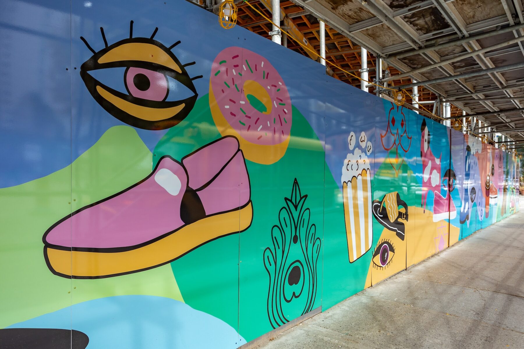 A colourful mural on a sidewalk wall with a large purple panel with written paragraphs.