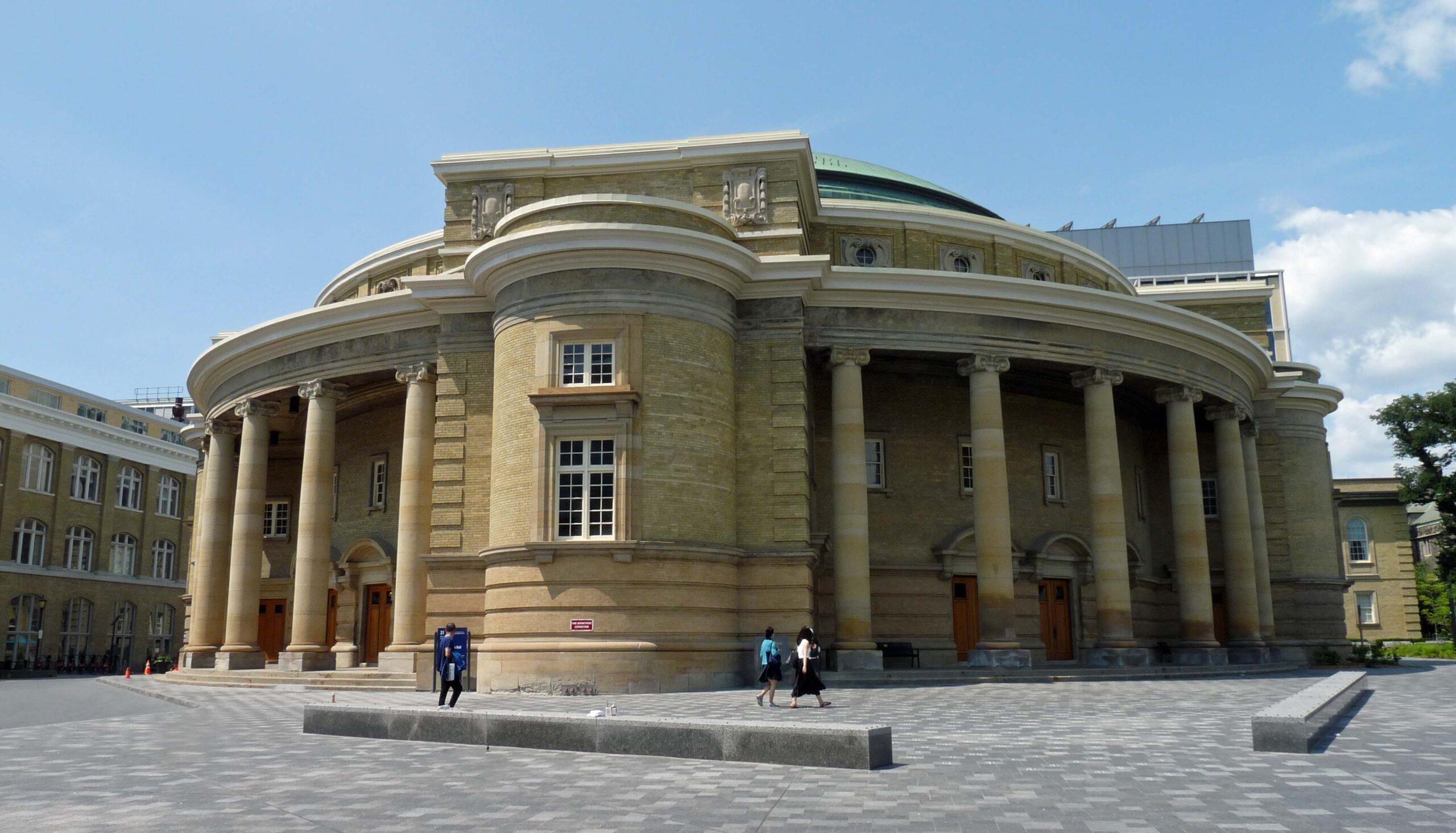 Large round yellow brick building with columns encompassing the structure on both sides.