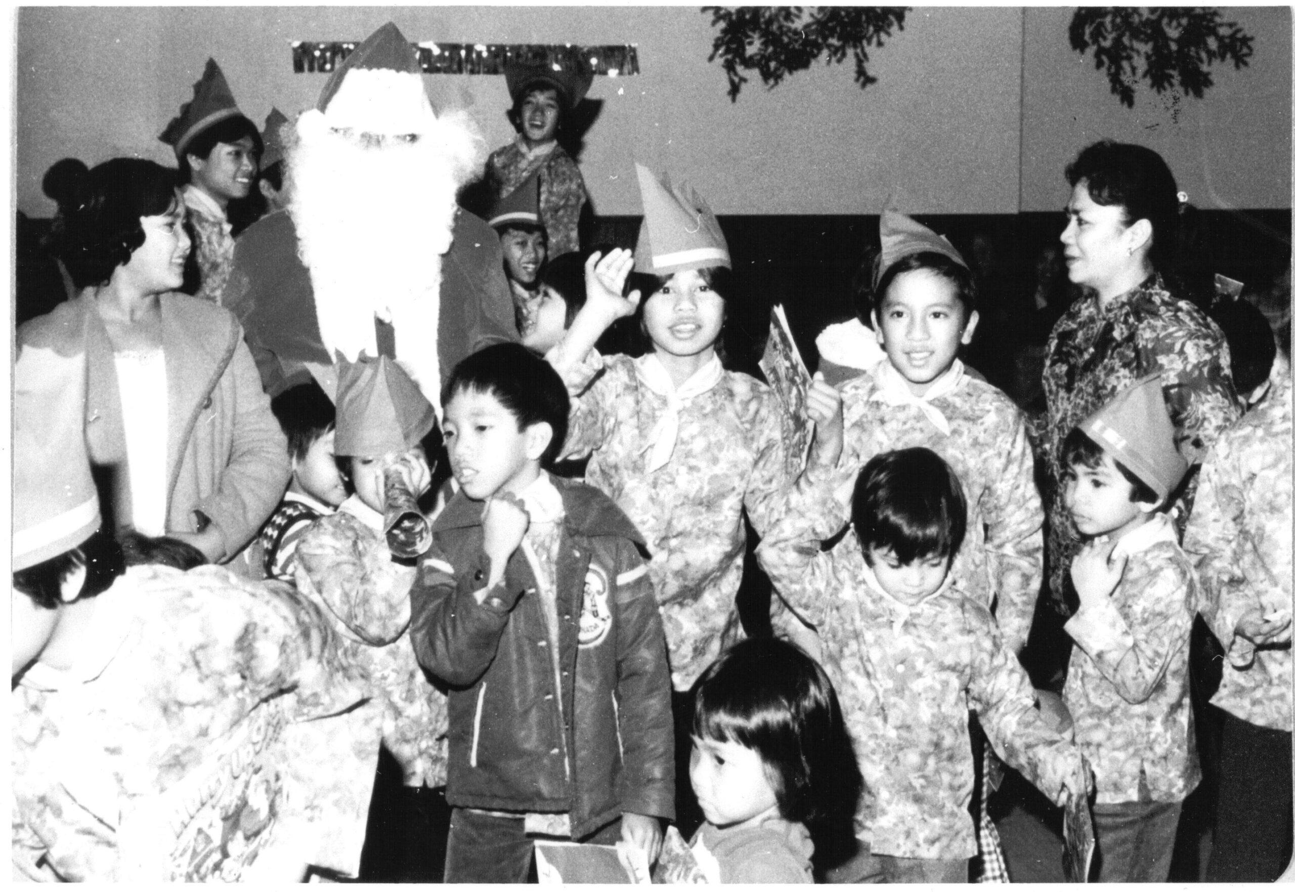 A black and white photograph of a group of Filipino children standing by Santa Claus at a Christmas celebration.