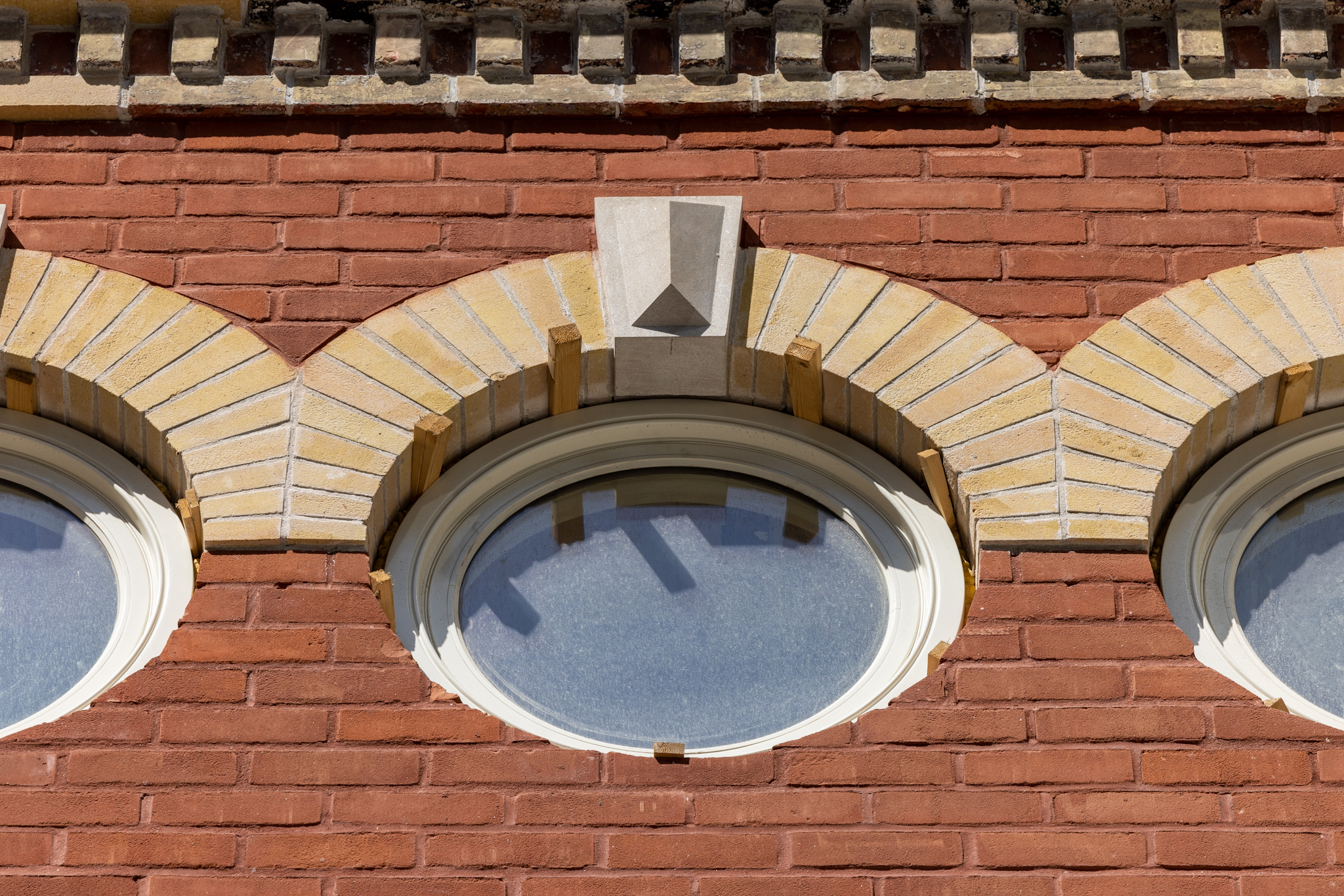 Close-up of restored yellow-brick archways and round windows on the red-brick façade of the historic IMMIX building.