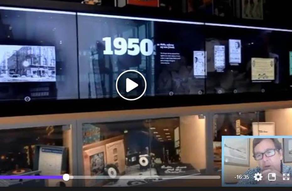 Screen shot of live stream showing display wall with interactive screen and displays of memorabilia
