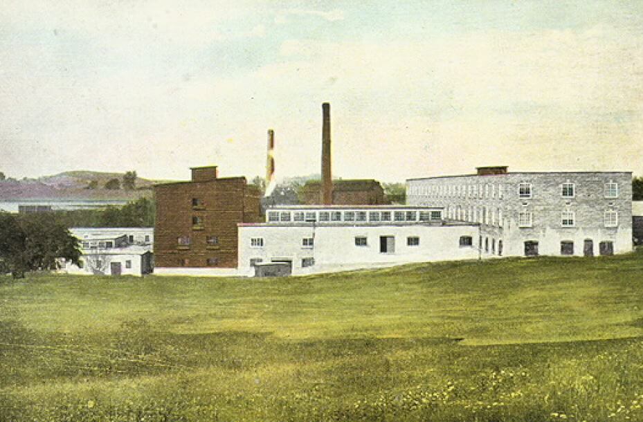 Colour image of an industrial complex, set within a countryside view. Text in a white border below the image reads - The Action tanning Co. Acton, ONT. Published by H.G. Hunter, Acton.