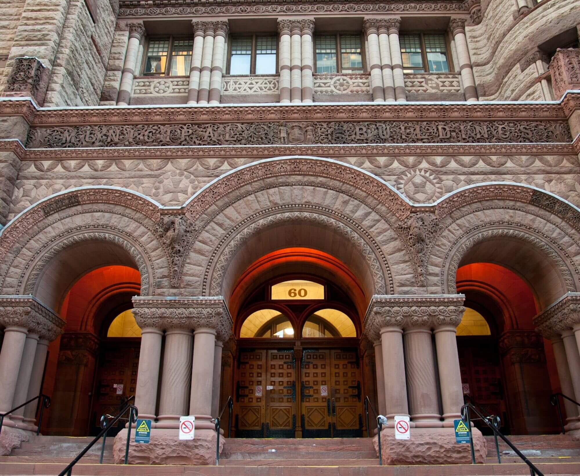 A large building that represents the Romanesque Revival architecture style, which features curved entrance ways, large stone, and ornate decoration.