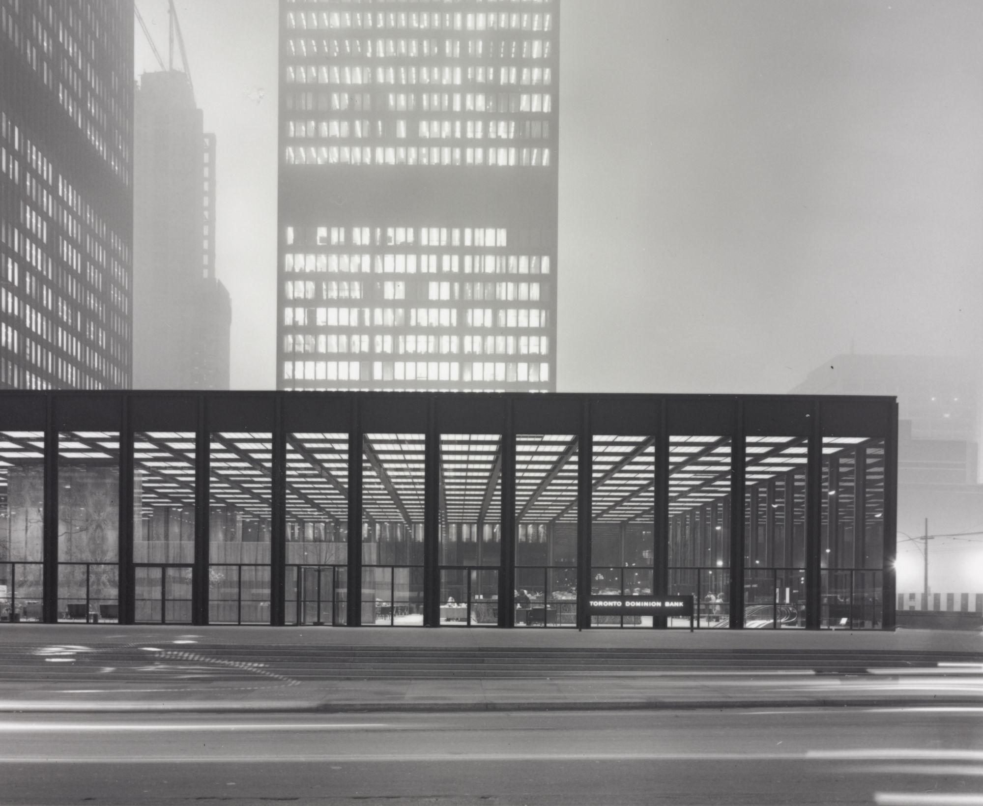 Black and white photograph shows pavilion, two completed towers, and one under construction of the Toronto-Dominion Centre by architect Mies van der Rohe.