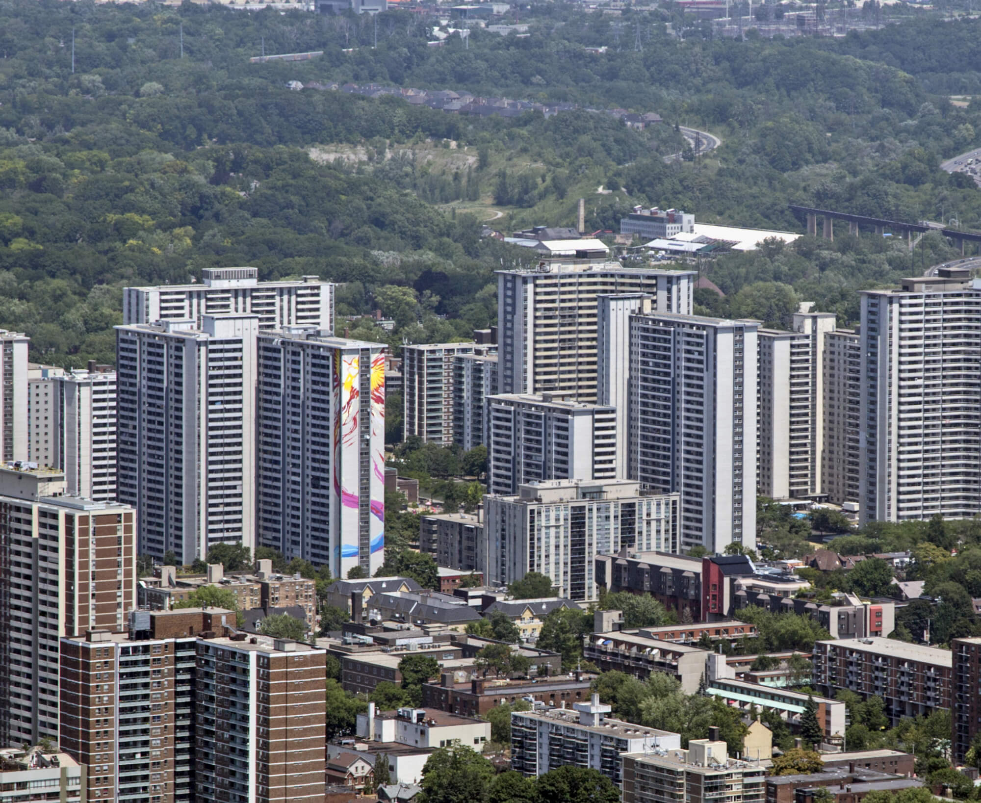 Colour aerial photograph of a cityscape with many tall residential buildings and complexes. Trees are visible in the background.
