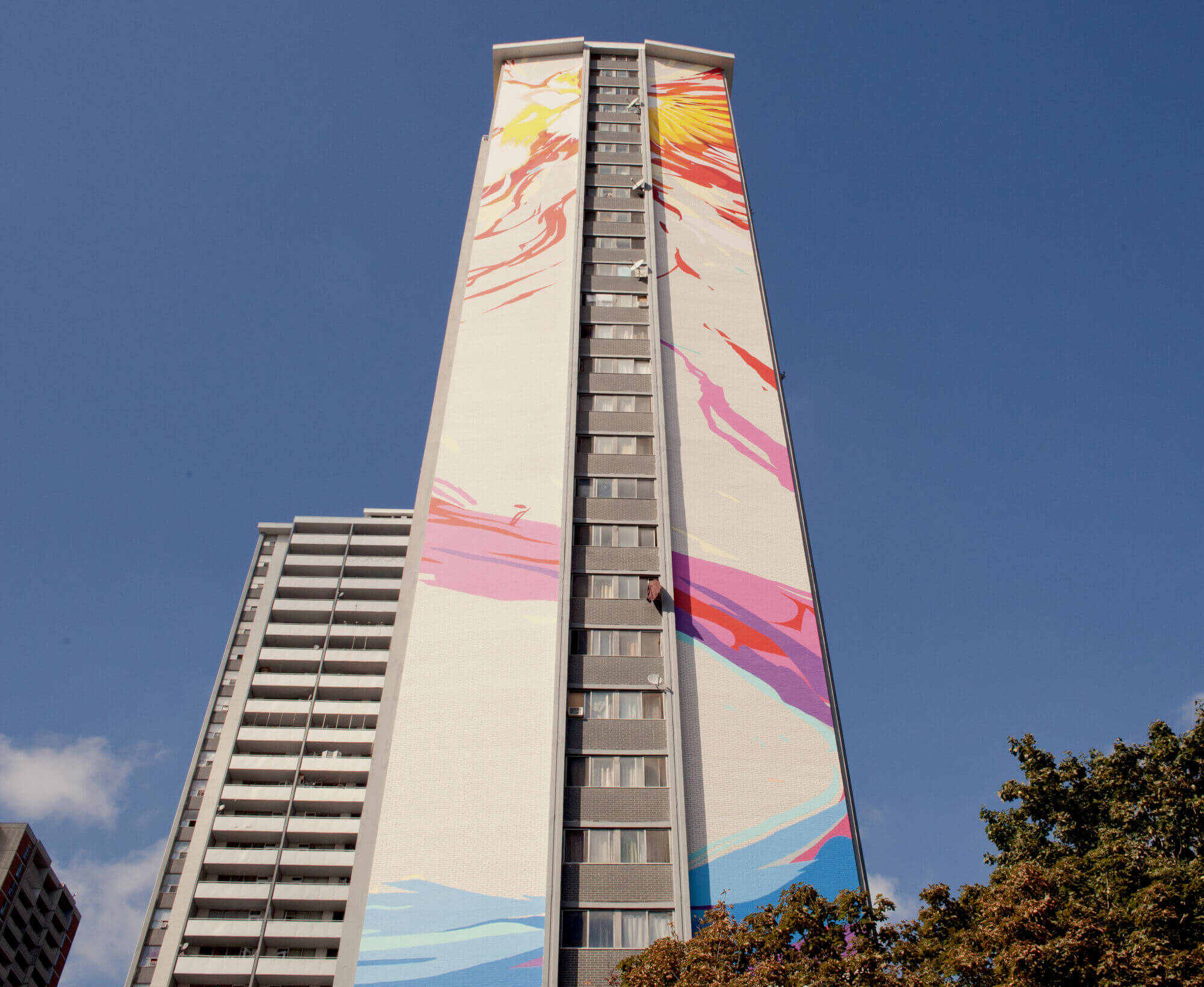 An exterior of a high-rise building with a colourful mural painting on its side.