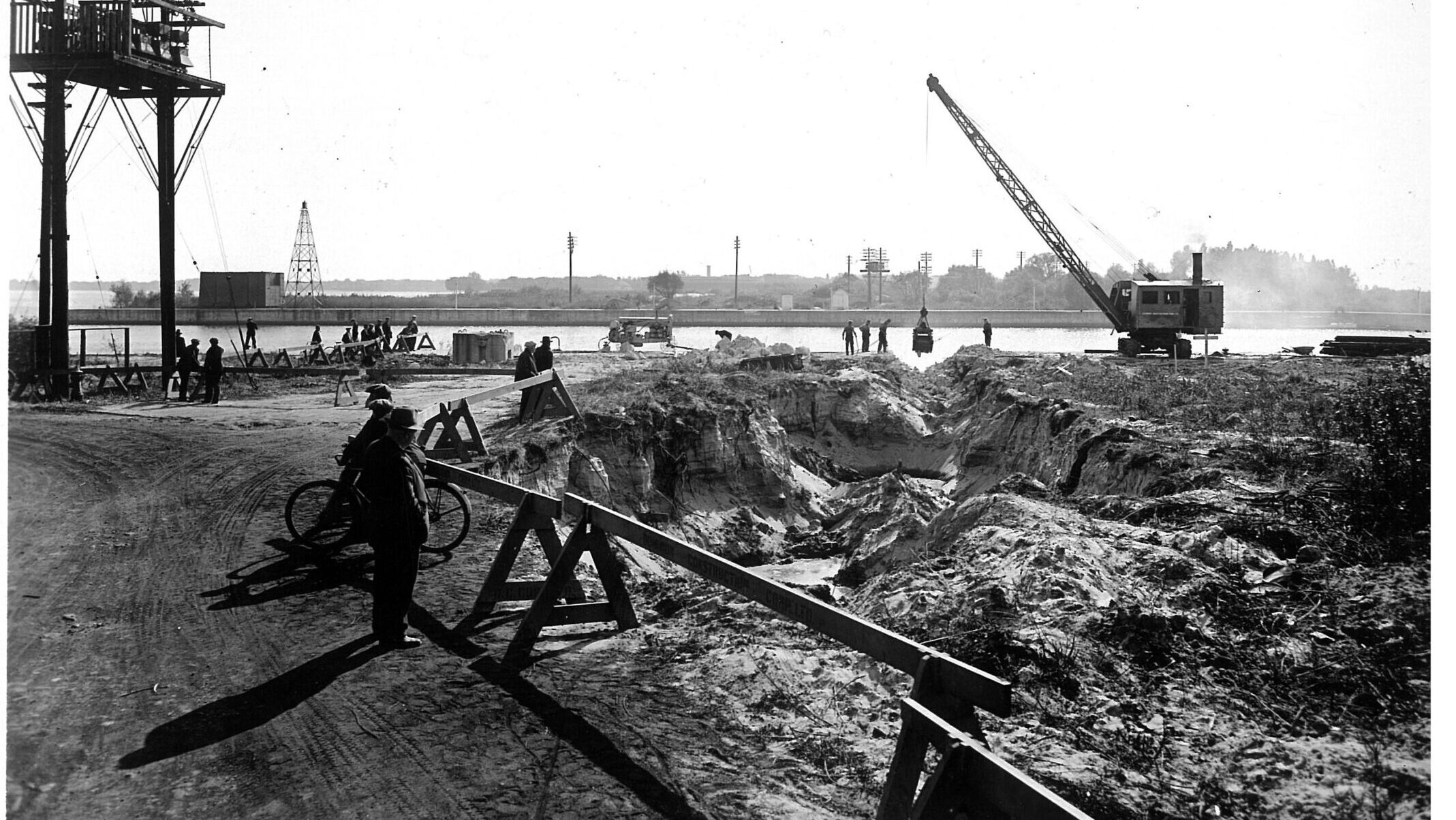 Black and white photograph of a tunnel excavation along the Western Gap with a crane and construction equipment in the back.