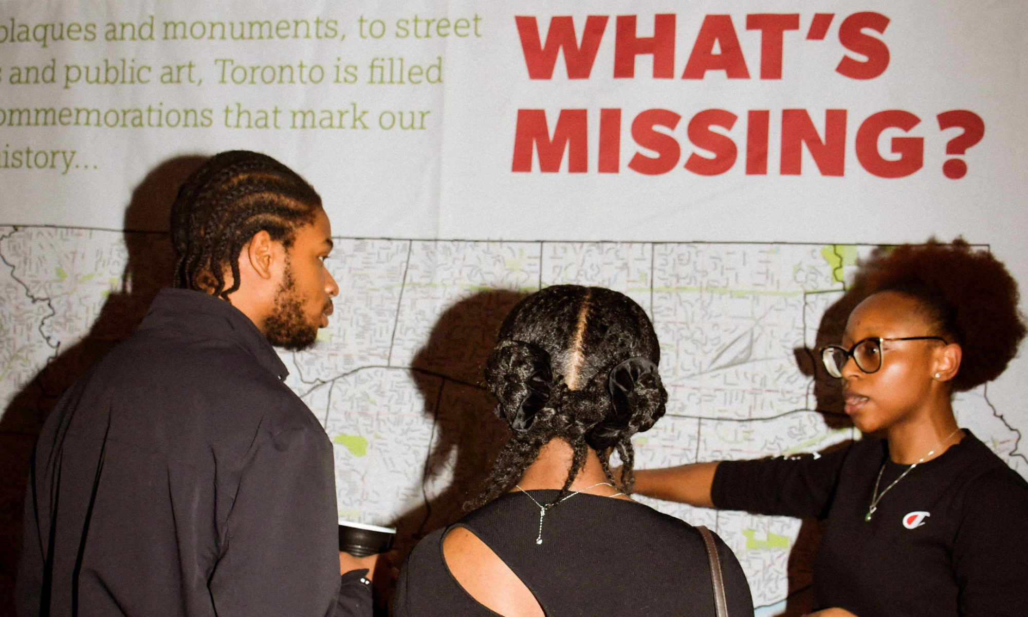Three people talking and looking at a map of Toronto that says "Whats Missing?"