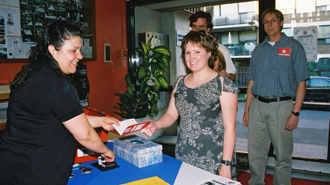 Before entering a pavilion, four people wait to have their festival passport stamped by a festival volunteer.