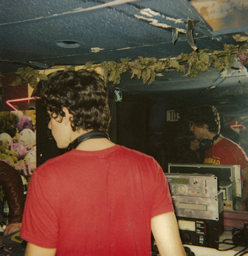 The back of a man wearing a red shirt and DJing.