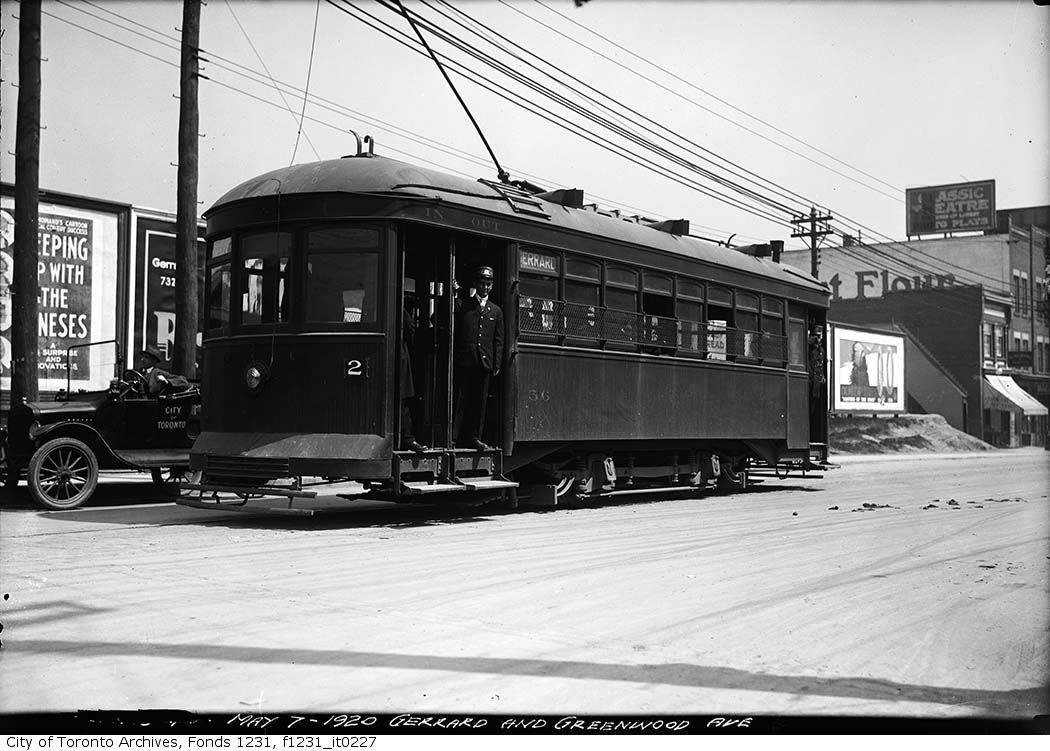A 20th century streetcar on a paved road. A caption reads "MAY 7-1920 GERRARD AND GREENWOOD AVE."