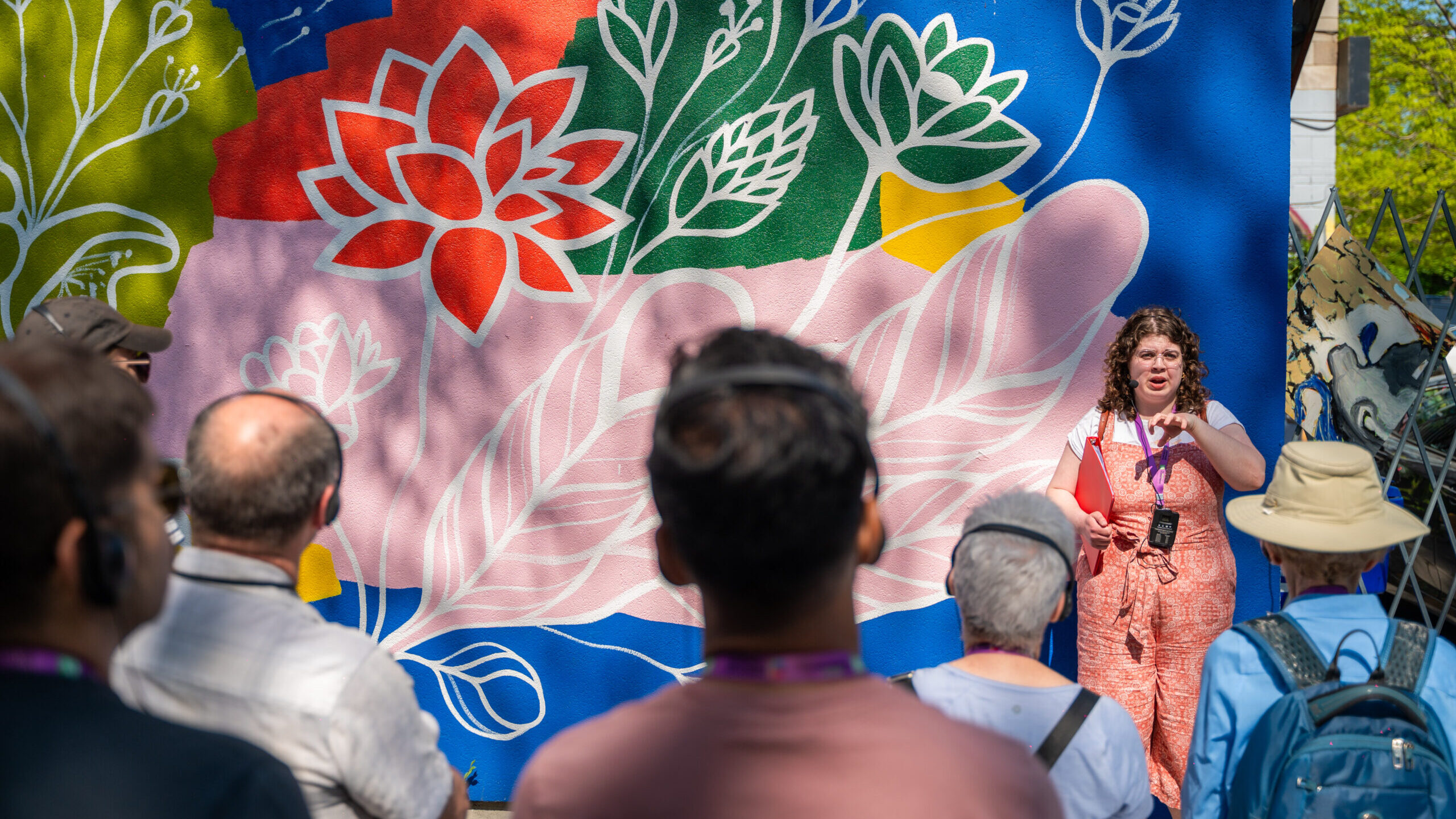A speaker stands in front of a floral wall mural.