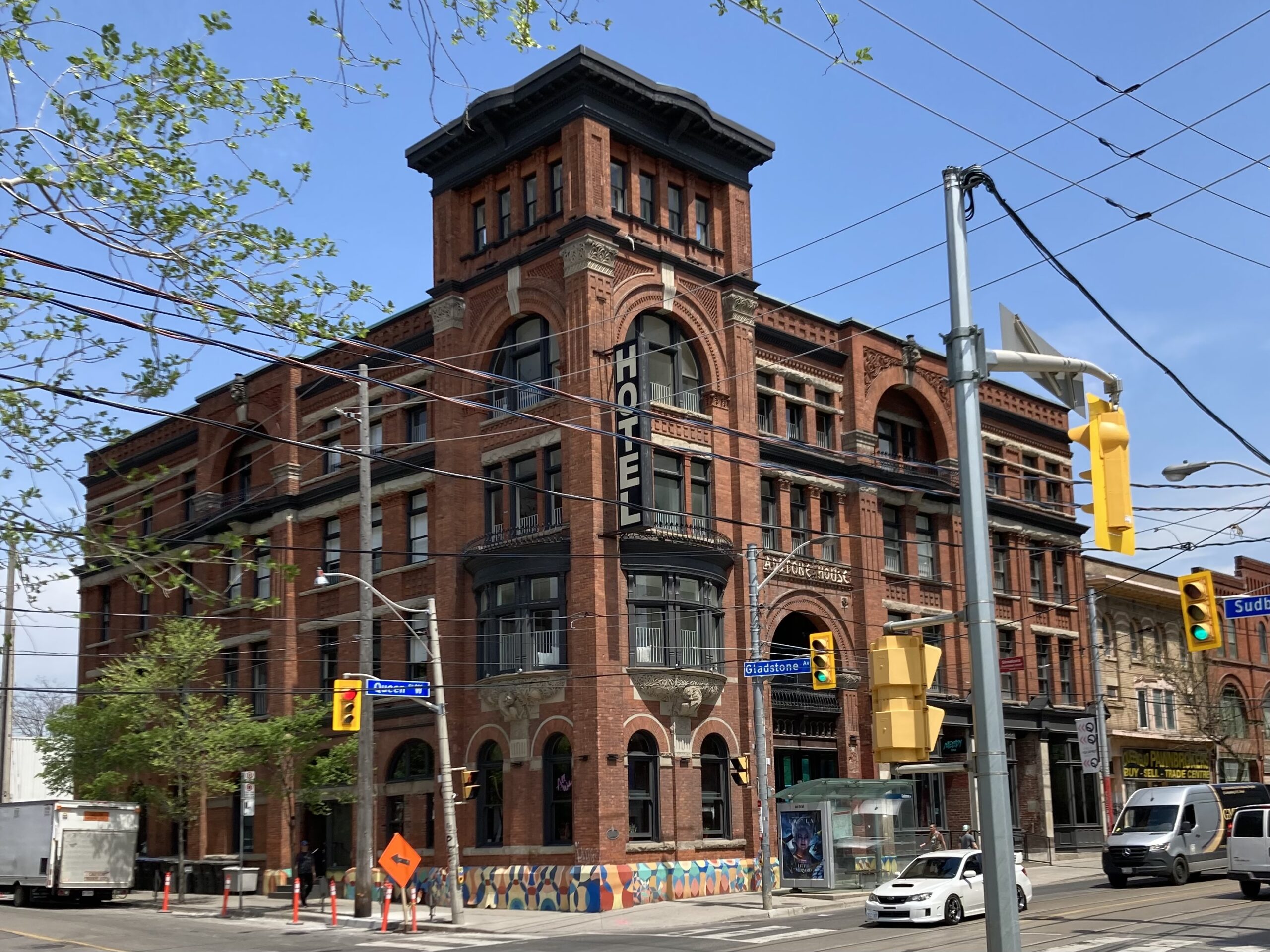 A large red brick building with arched windows. A black sign sticking out of the building reads "hotel."