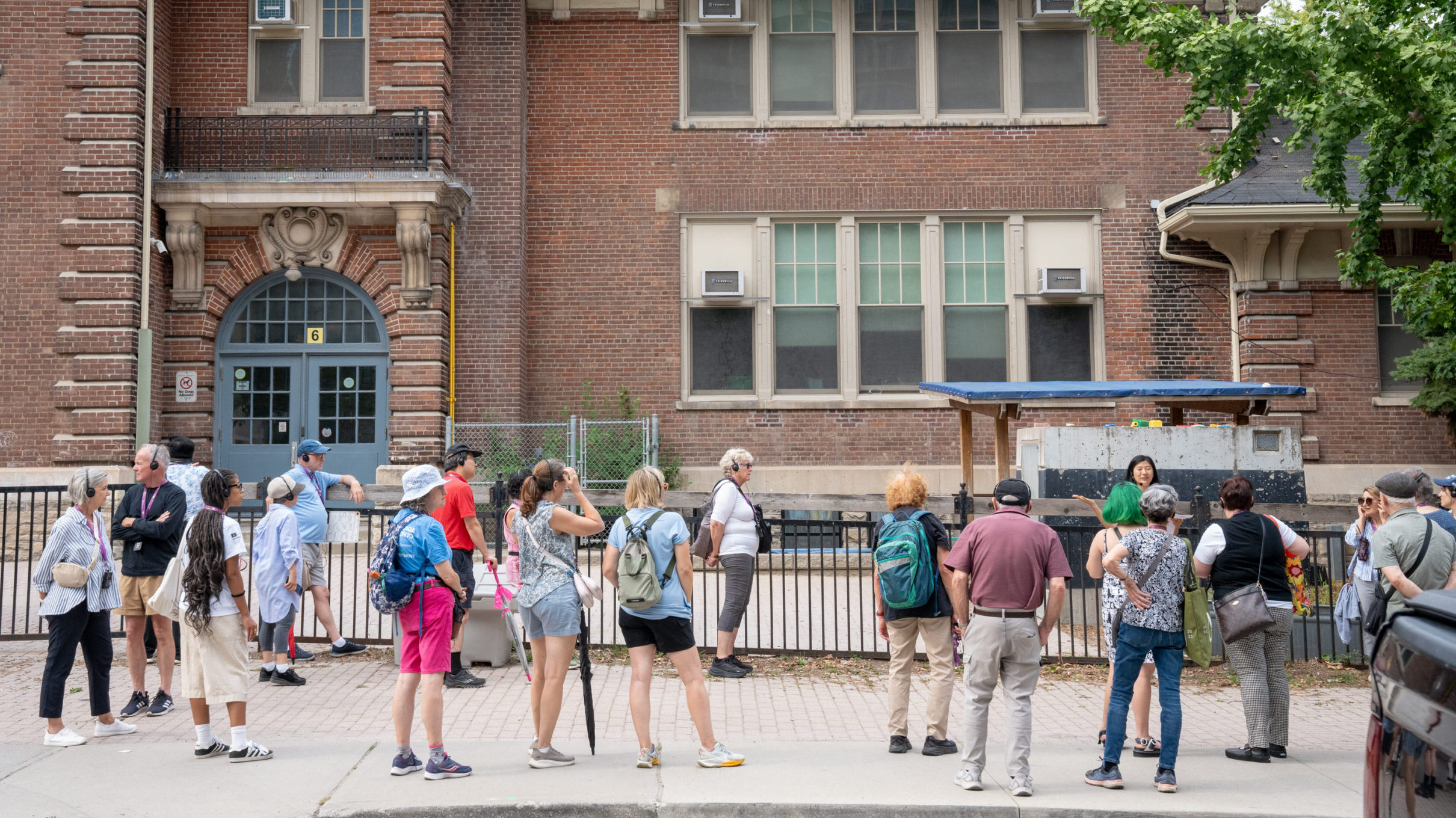 A group of people stand in front of a brick building.