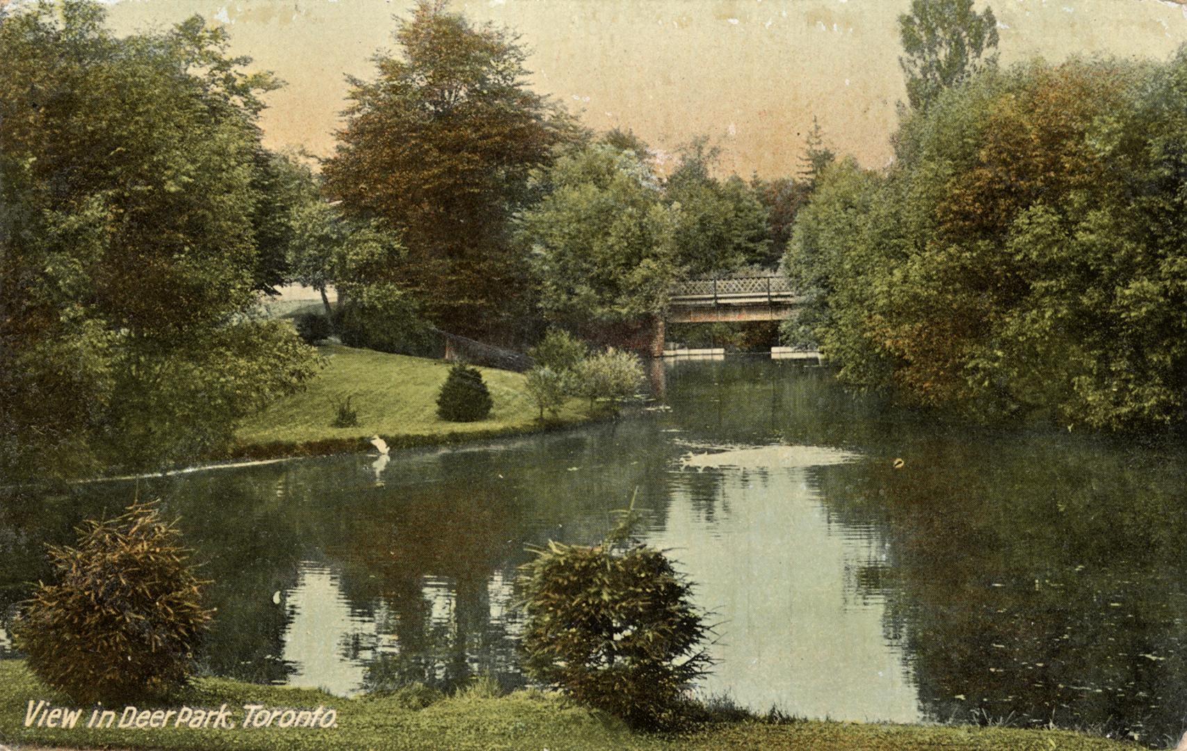 A manicured creek with water and a bridge in the distance. Text on the bottom left corner reads “View in Deer Park, Toronto.”