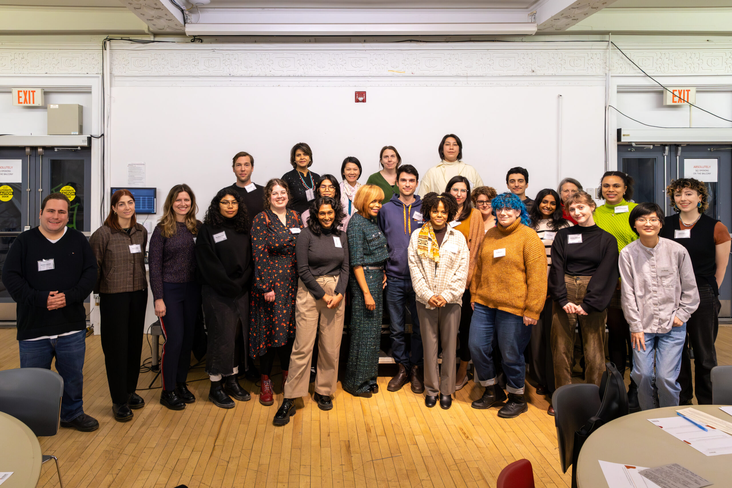 25 people stand in mulitple rows and smile for the camera.