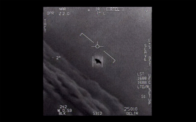 Black and white image showing a central indicator in which a dark saucer-shaped visual appears. Various measurements in white text appear on the image borders, with white cloud-like formations visible along a diagonal at the lower right.
