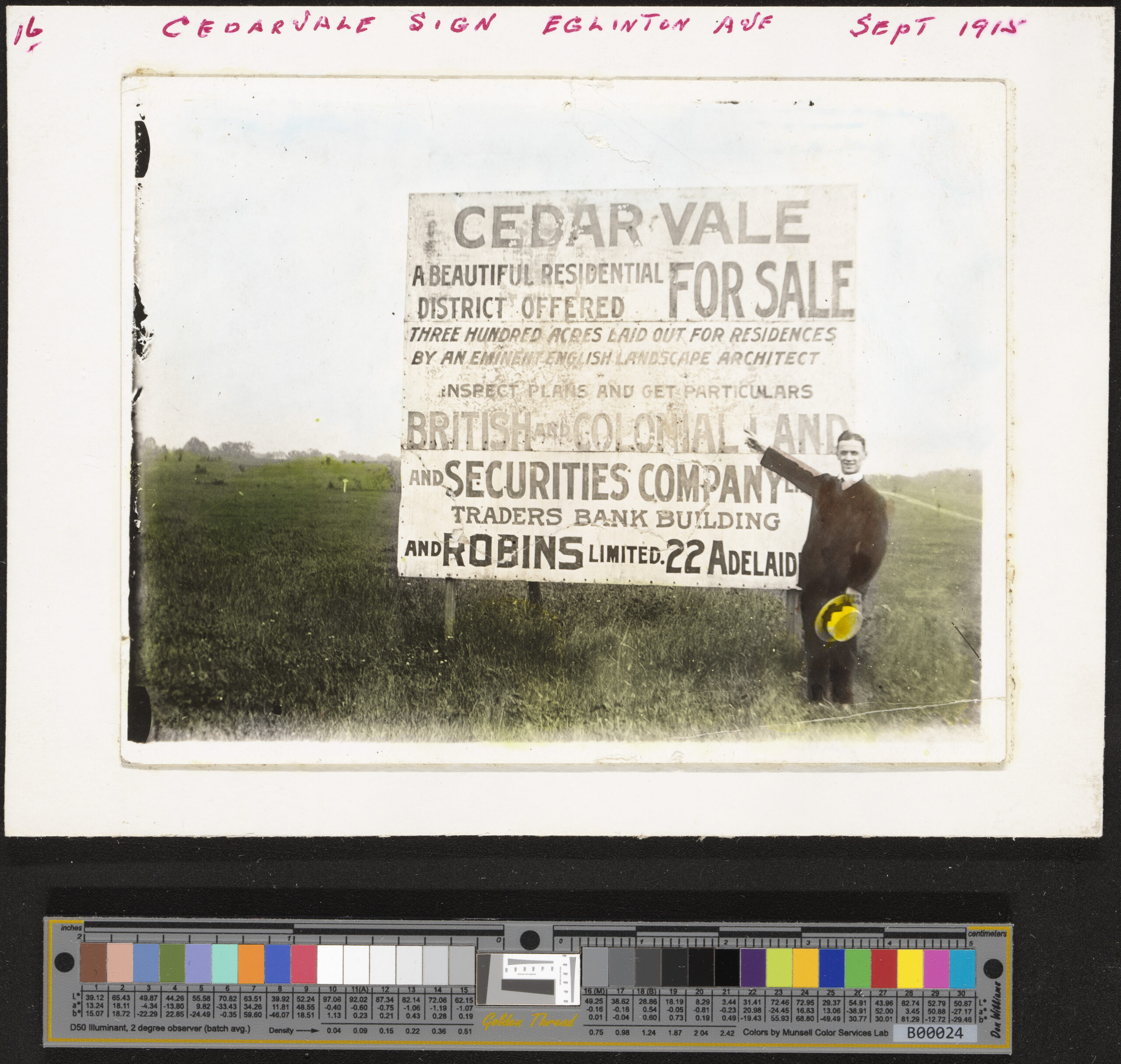 Image of Man standing in a cleared field and pointing at a large sign that reads CEDARVALE FOR SALE.